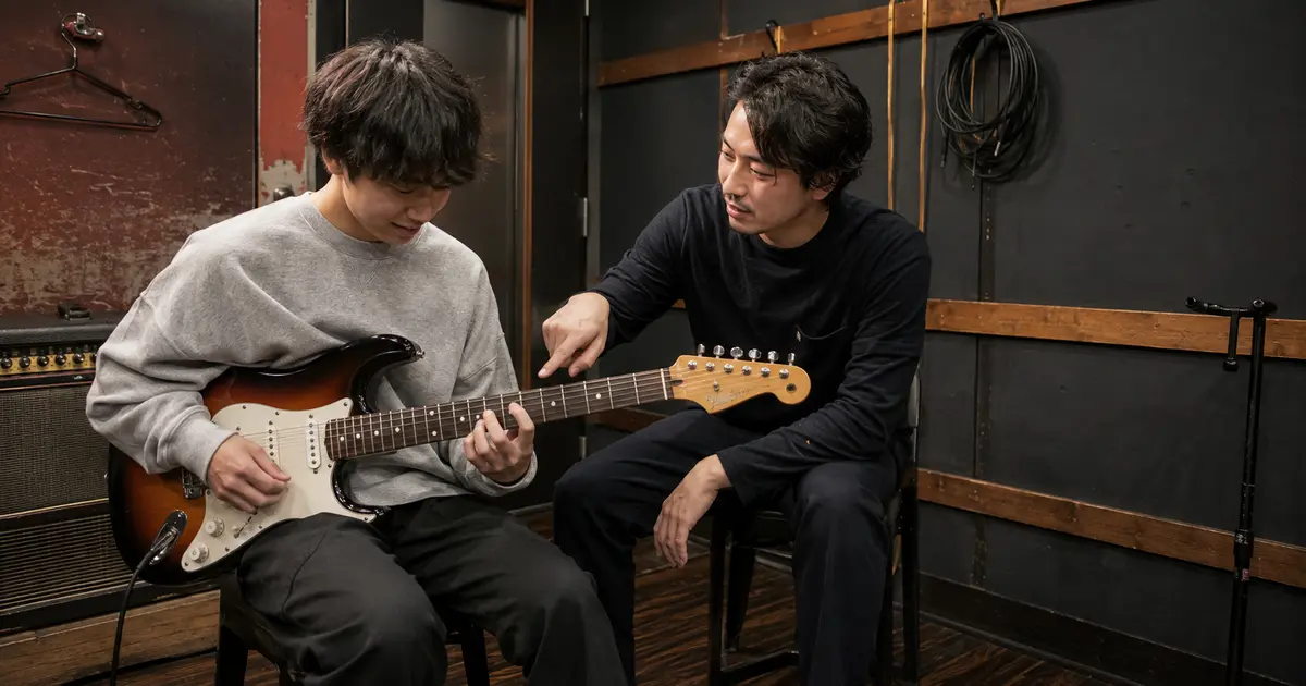 音楽スタジオでホストに教わりながらエレキギターを弾く初心者の男性